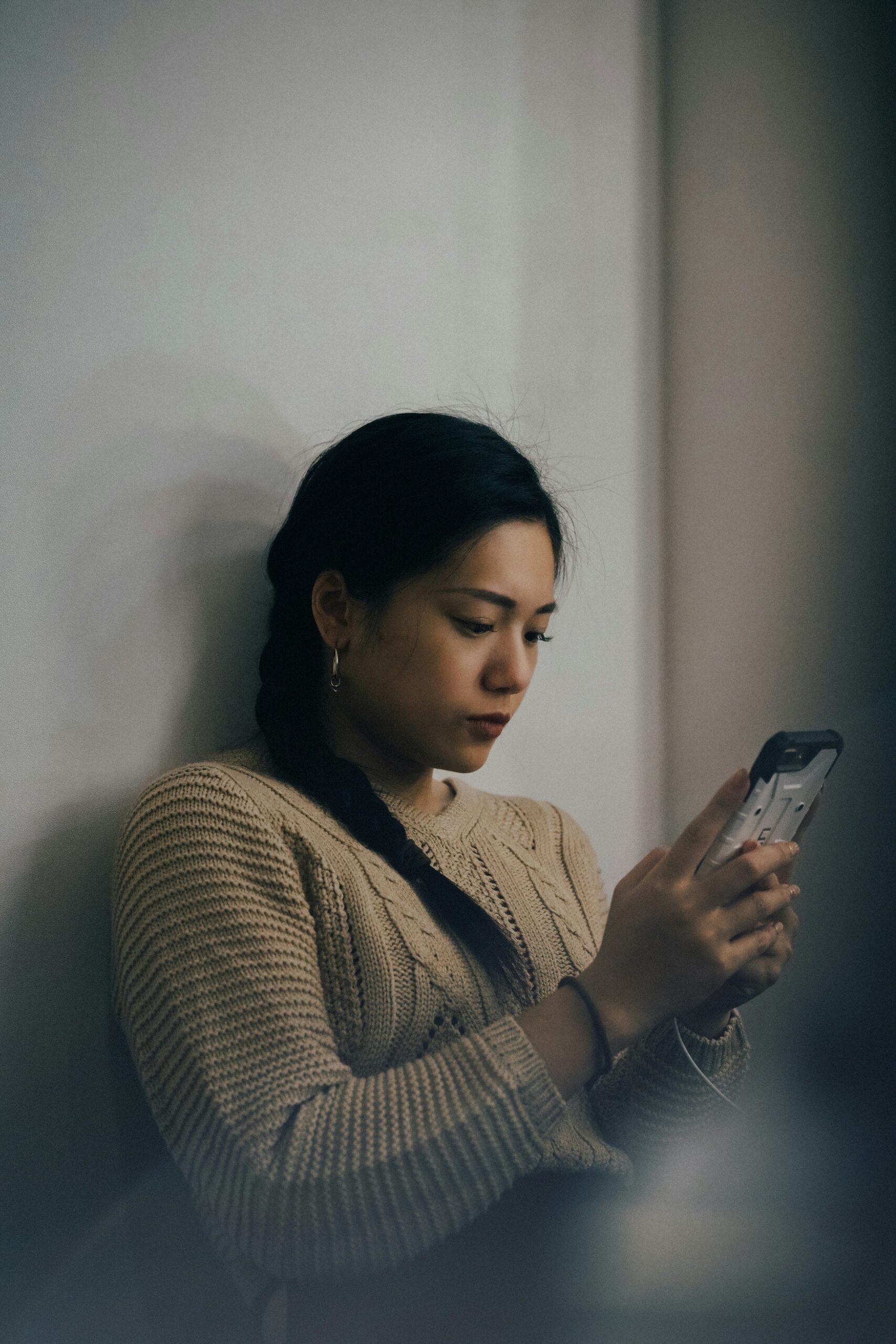 woman sitting on the floor looking at her phone