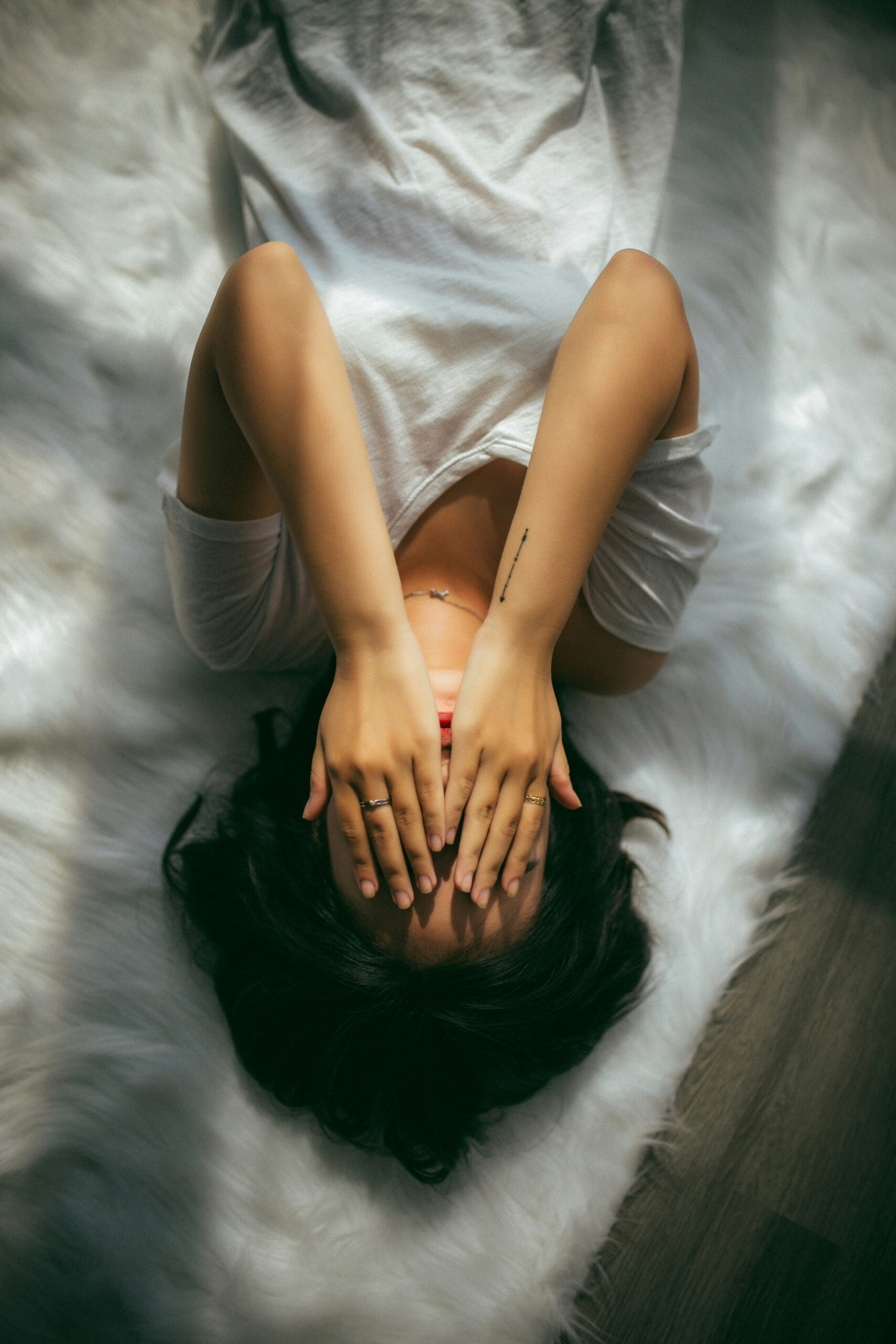 woman laying on bed with hands over face. burnout is real, therapy can help.