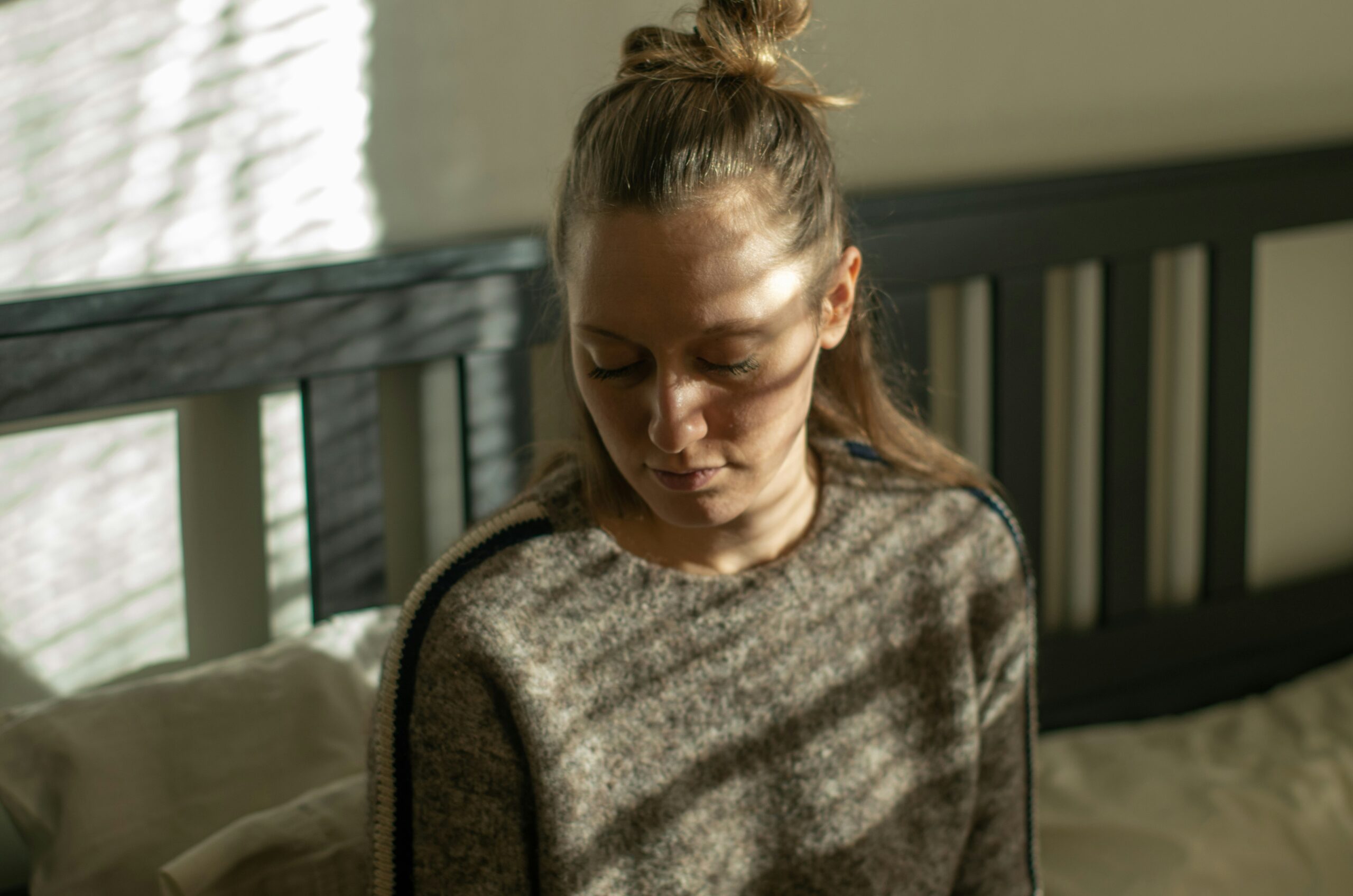 woman sitting on bed looking down