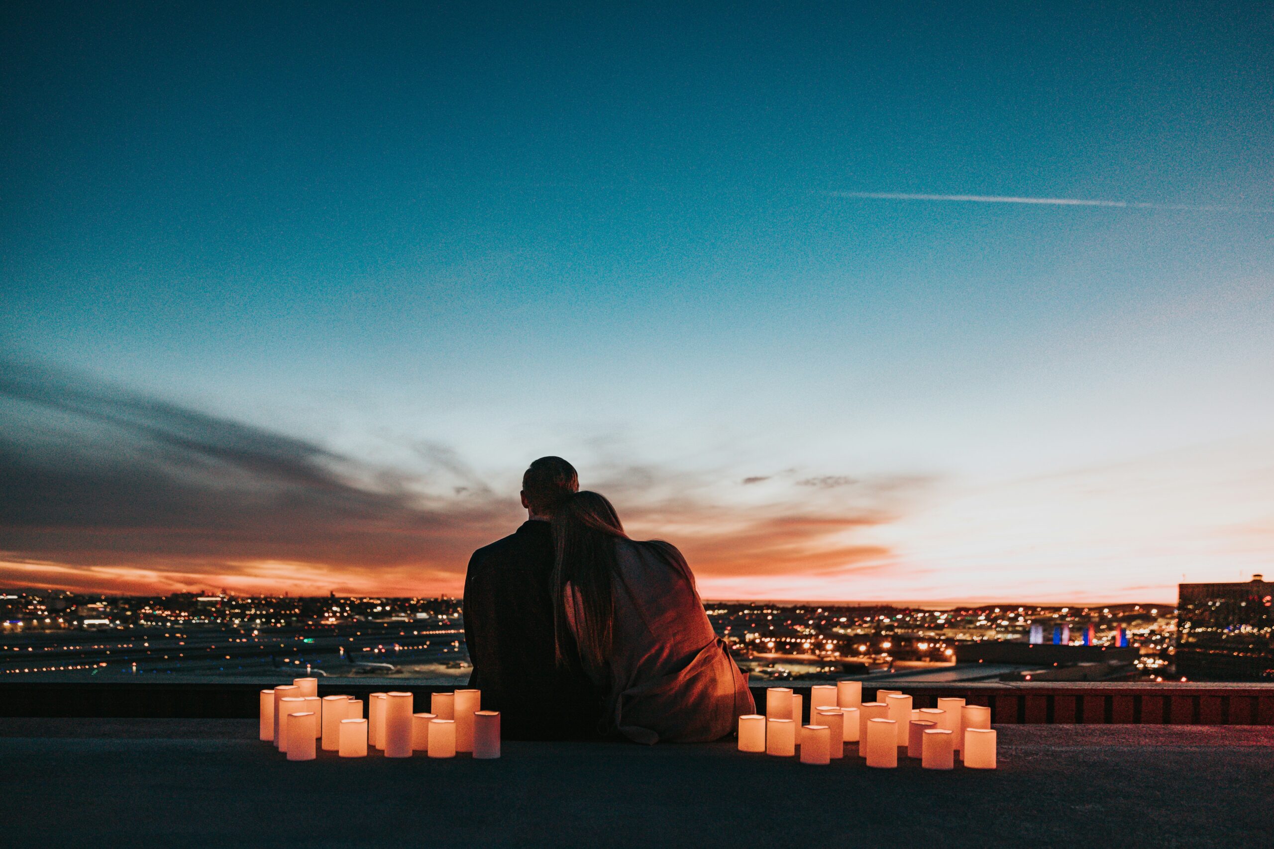Manhattan couple sitting with candles surrounding them, communicating at sunset.