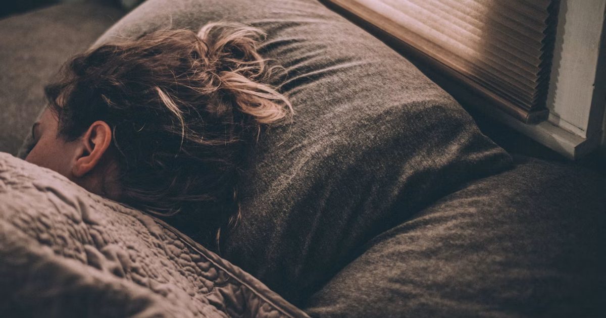Woman lying awake in bed with racing thoughts at night